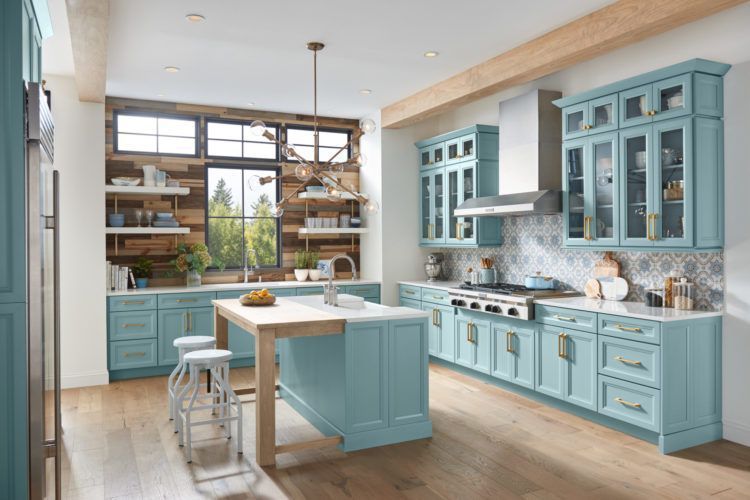 Bright modern kitchen with teal cabinets, white island, open shelving, and large windows