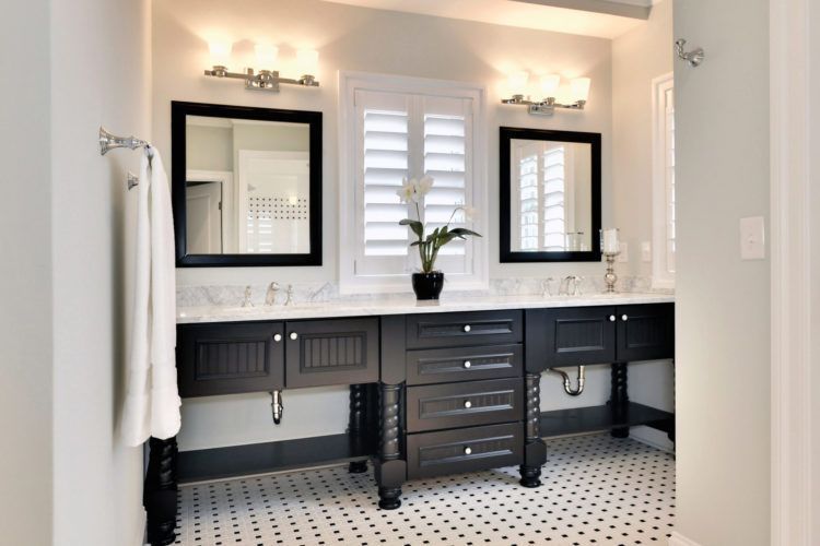 Modern bathroom with double black vanity, mirrors, wall sconces, and patterned tile floor