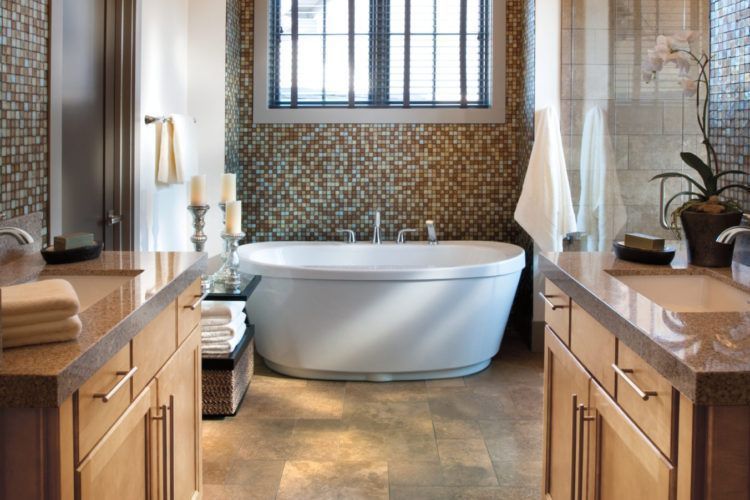 Modern bathroom with a freestanding tub, mosaic tile wall, and wood cabinetry on both sides