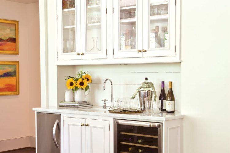 Modern white kitchen bar with sink, cabinets, wine fridge, and sunflowers on the counter