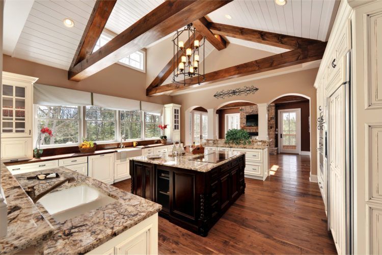 Bright kitchen with granite island, white cabinets, wood beams, and hardwood floors