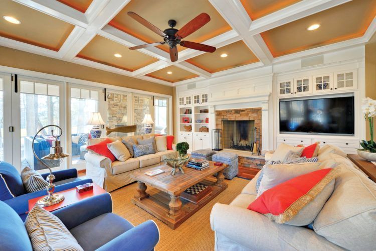 Bright living room with beige sofas, blue chairs, wooden coffee table, fireplace, and large TV