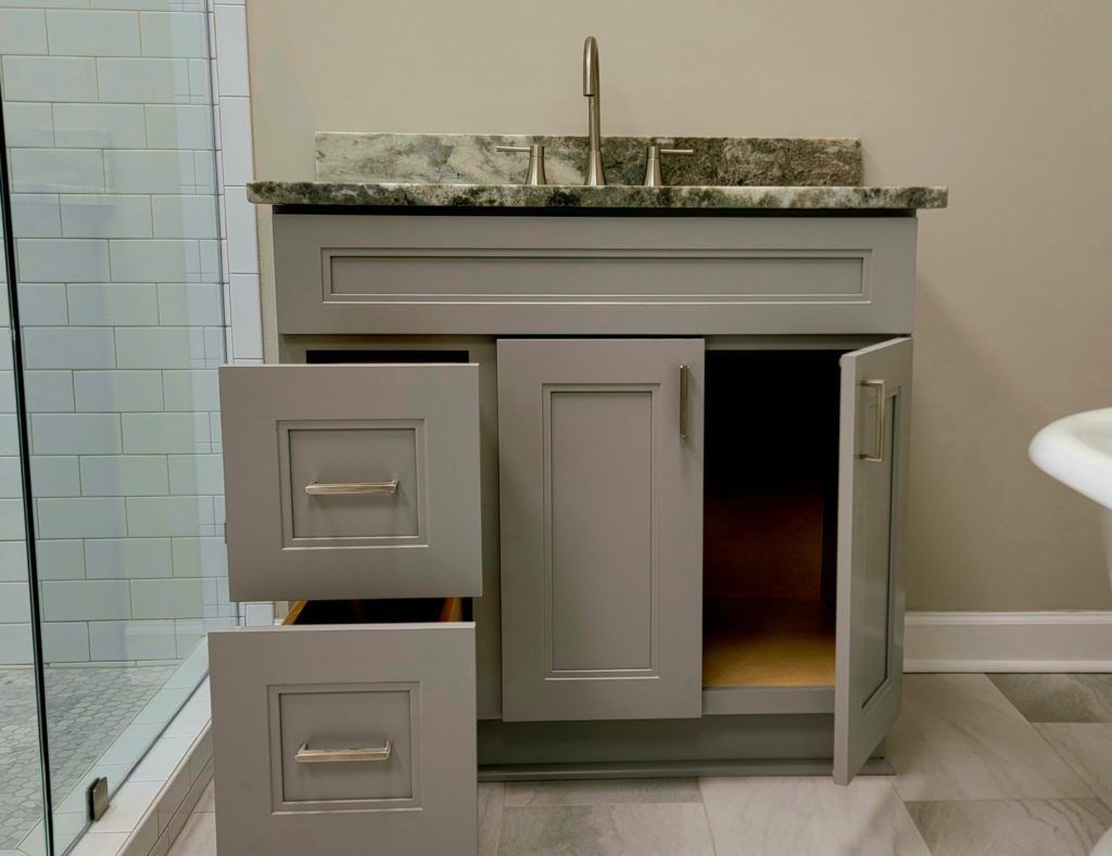 Bathroom vanity with granite countertop, sink, open cabinet doors, and two drawers in gray cabinetry
