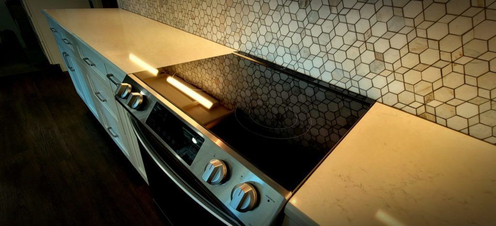 Modern kitchen with stainless steel stove and honeycomb tile backsplash, viewed from an angle