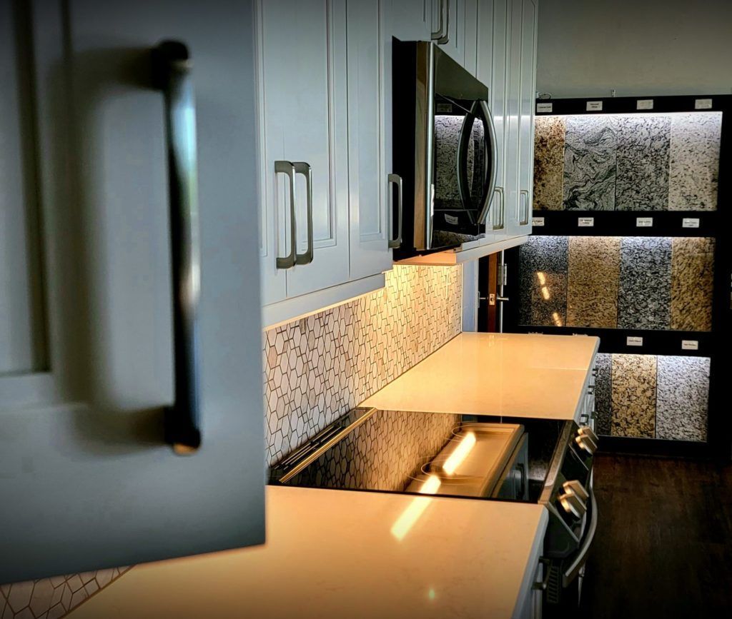 Modern kitchen with beige countertops, dark cabinets, patterned backsplash, and stainless steel appliances
