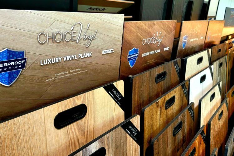 Wooden vinyl plank display samples with cutout handles and brand labels in a showroom rack
