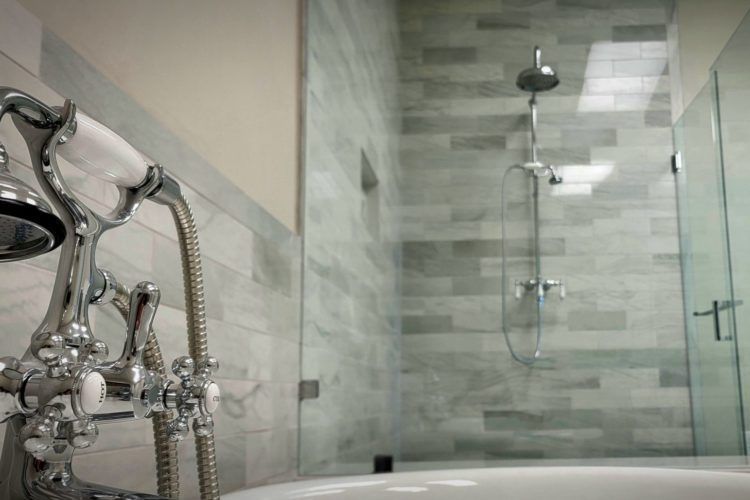 Modern bathroom with a glass shower, chrome fixtures, and gray tile walls