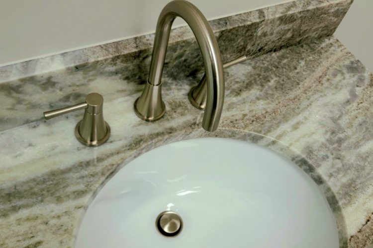 Bathroom sink with brushed nickel faucet and soap dispenser on marble countertop