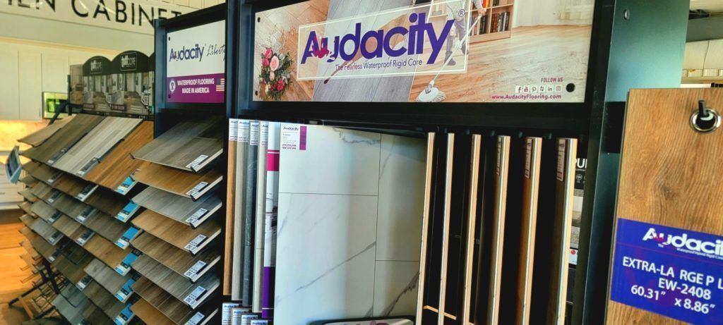 Audacity-branded display booth with shelves of flooring samples and product signage