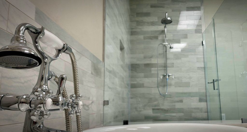 Modern bathroom with glass shower, chrome faucet, and gray tiled walls