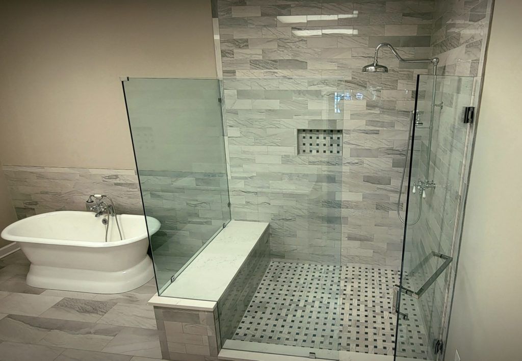 Modern bathroom with a freestanding tub, glass shower, and gray tile walls and floor