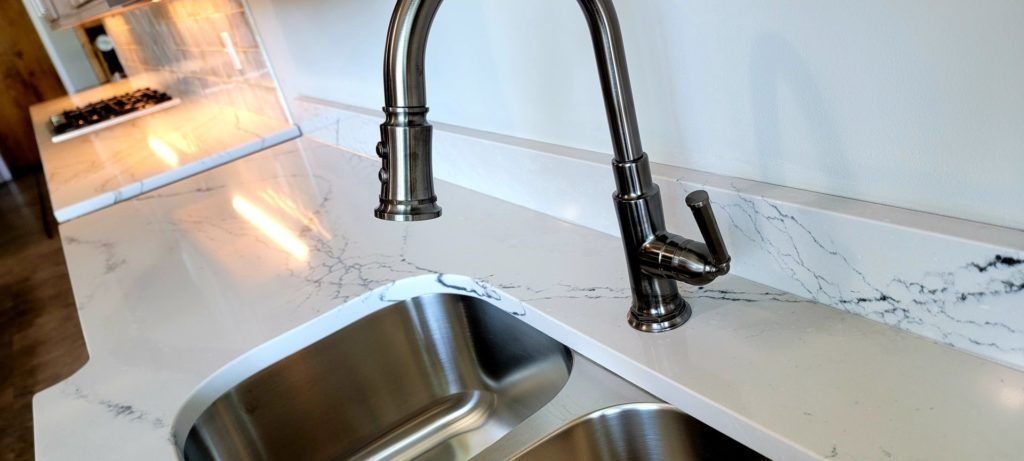 Kitchen sink with black faucet and bright countertop beside a window