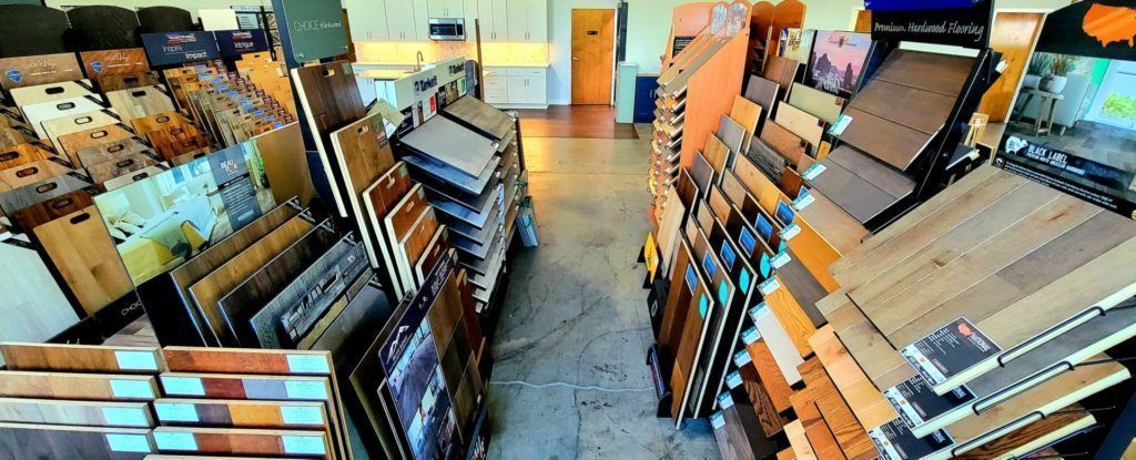 Hardware store aisle with stacked wood and shelves of roofing materials on both sides