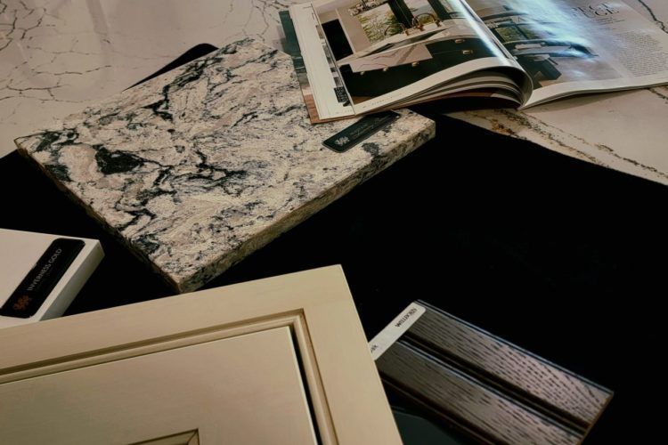 Assorted interior design sample books and swatches spread across a dark table.