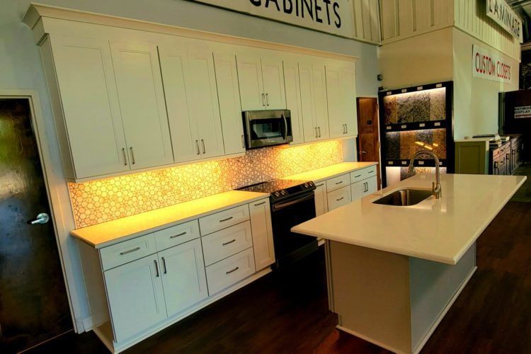 Modern kitchen display with white cabinets, large island, and under-cabinet lighting