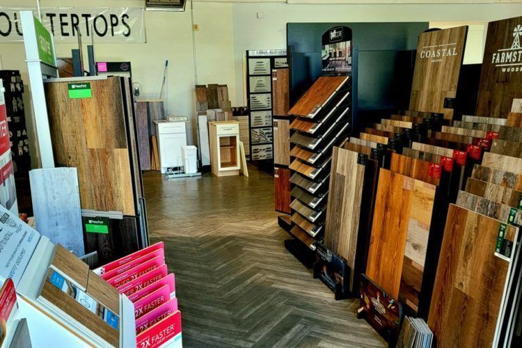 Wood flooring showroom with sample boards, displays, and herringbone-patterned floor in the background