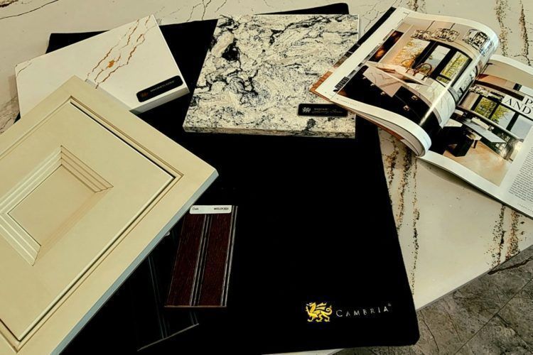Assorted interior design sample books and material swatches spread on a table