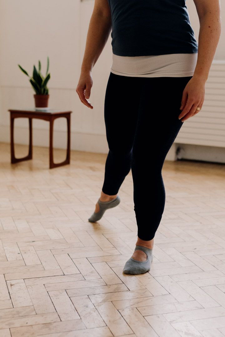 photo of a person wearing sports clothing standing on one leg with the other leg behind them