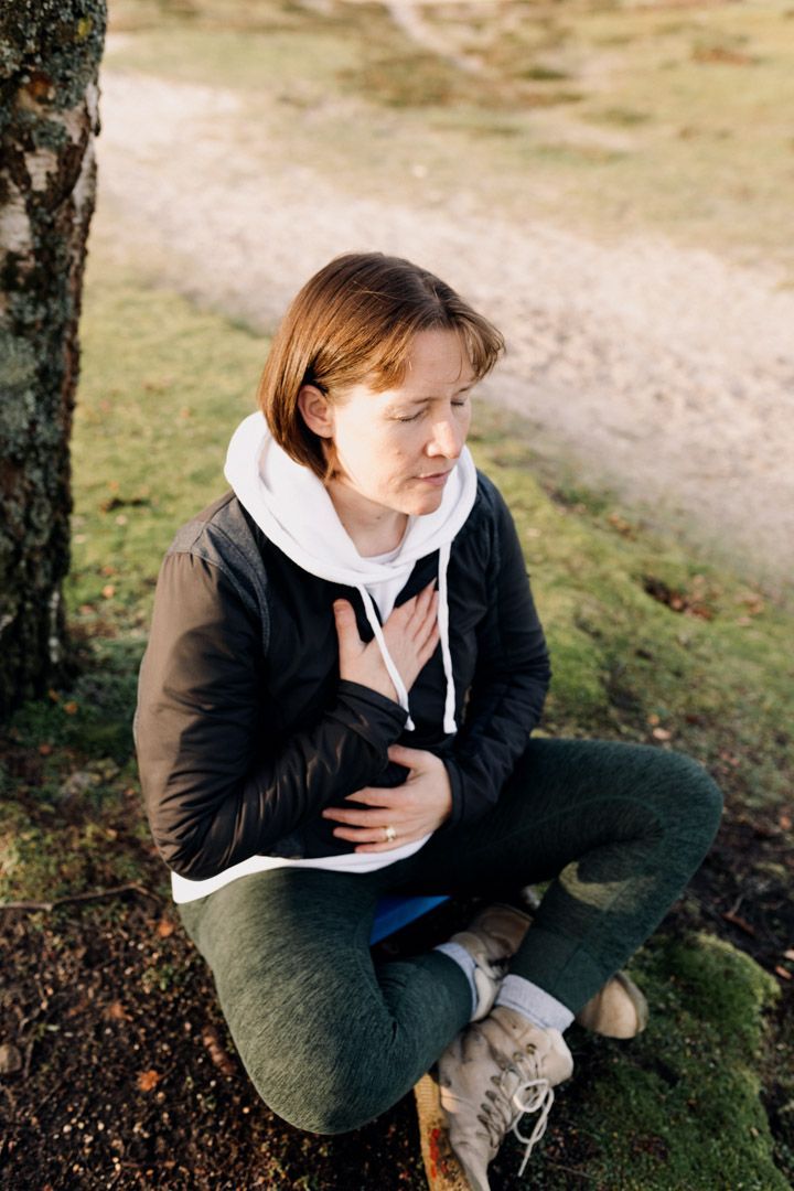 photo of lady sitting by a tree, hands over chest and relaxing