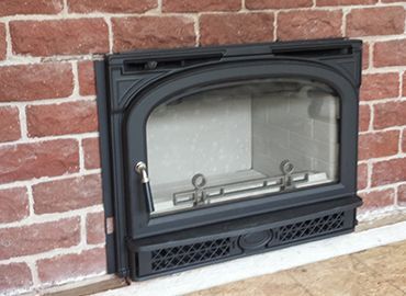 A fireplace is built into a red brick wall.