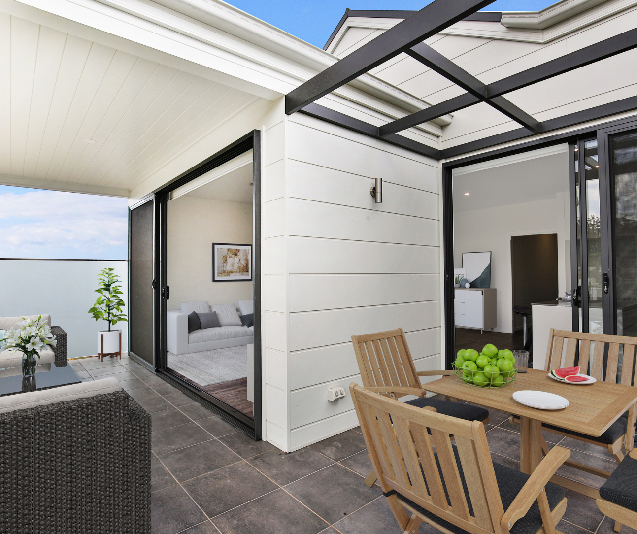 Modern patio with wooden dining set, black pergola, sliding glass doors, and view into a bedroom
