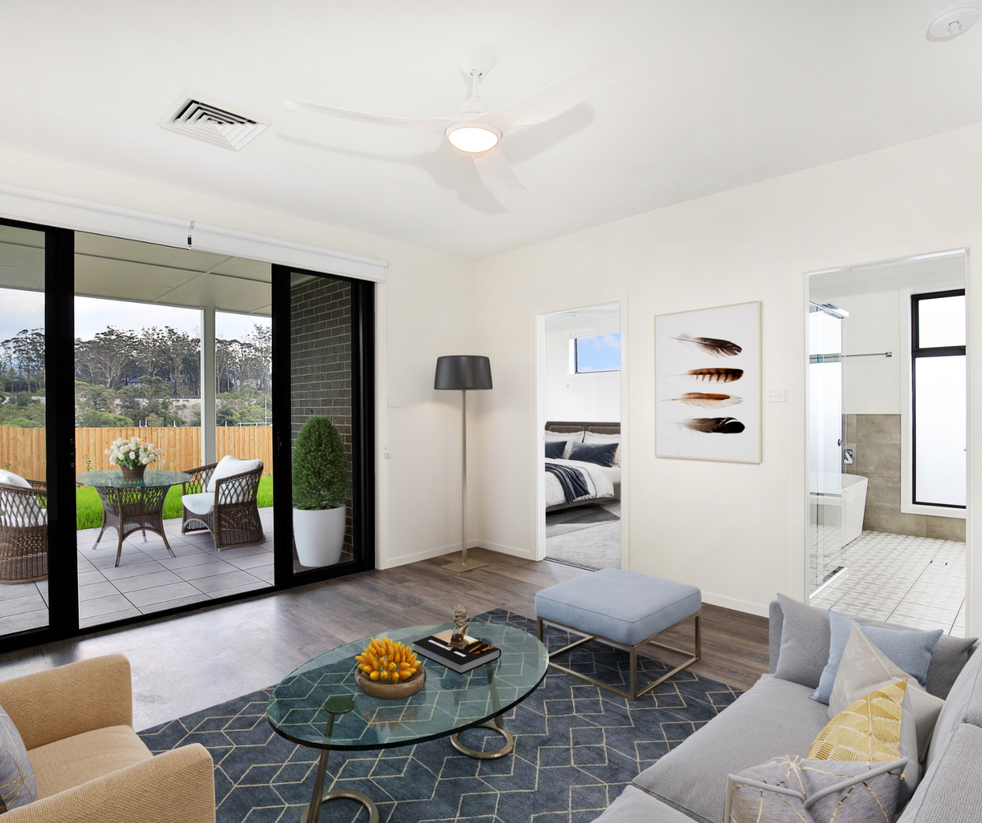 Bright modern living room with gray sofa, patterned rug, and sliding doors to a patio and outdoor seating