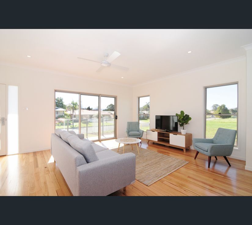 Living room with light-colored walls, wooden floor, gray sofa, and blue armchairs. Sliding glass doors lead to outdoors.