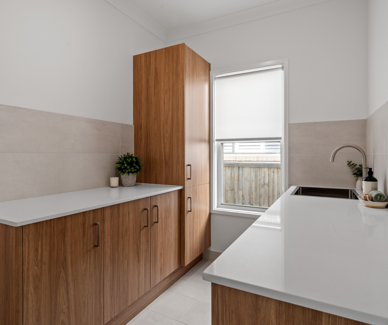 Modern kitchen with wooden cabinets, white countertops, and a window with a blind. Modern kitchen with wooden cabinets, white countertops, and a window with a blind.