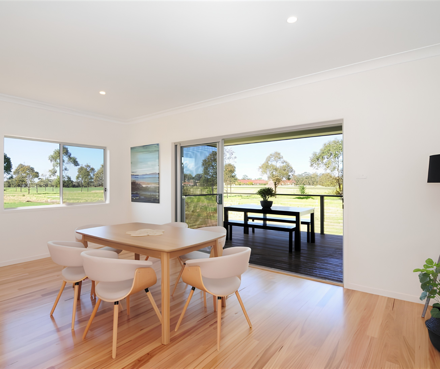 Bright dining room with wooden table, chairs, and large windows overlooking a grassy backyard. Bright dining room with wooden table, chairs, and large windows overlooking a grassy backyard.