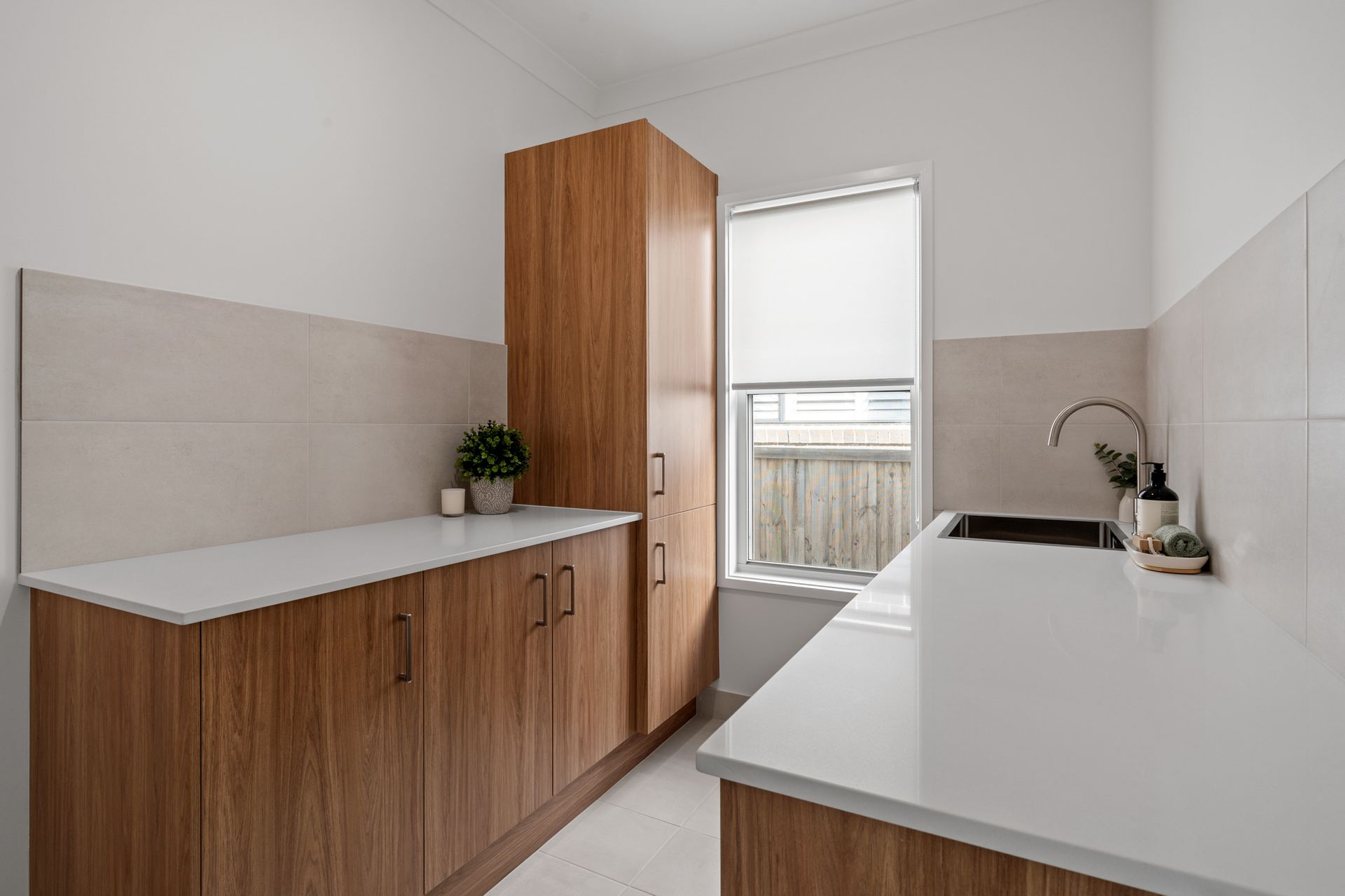 Laundry room with wooden cabinets, white countertop, and window.