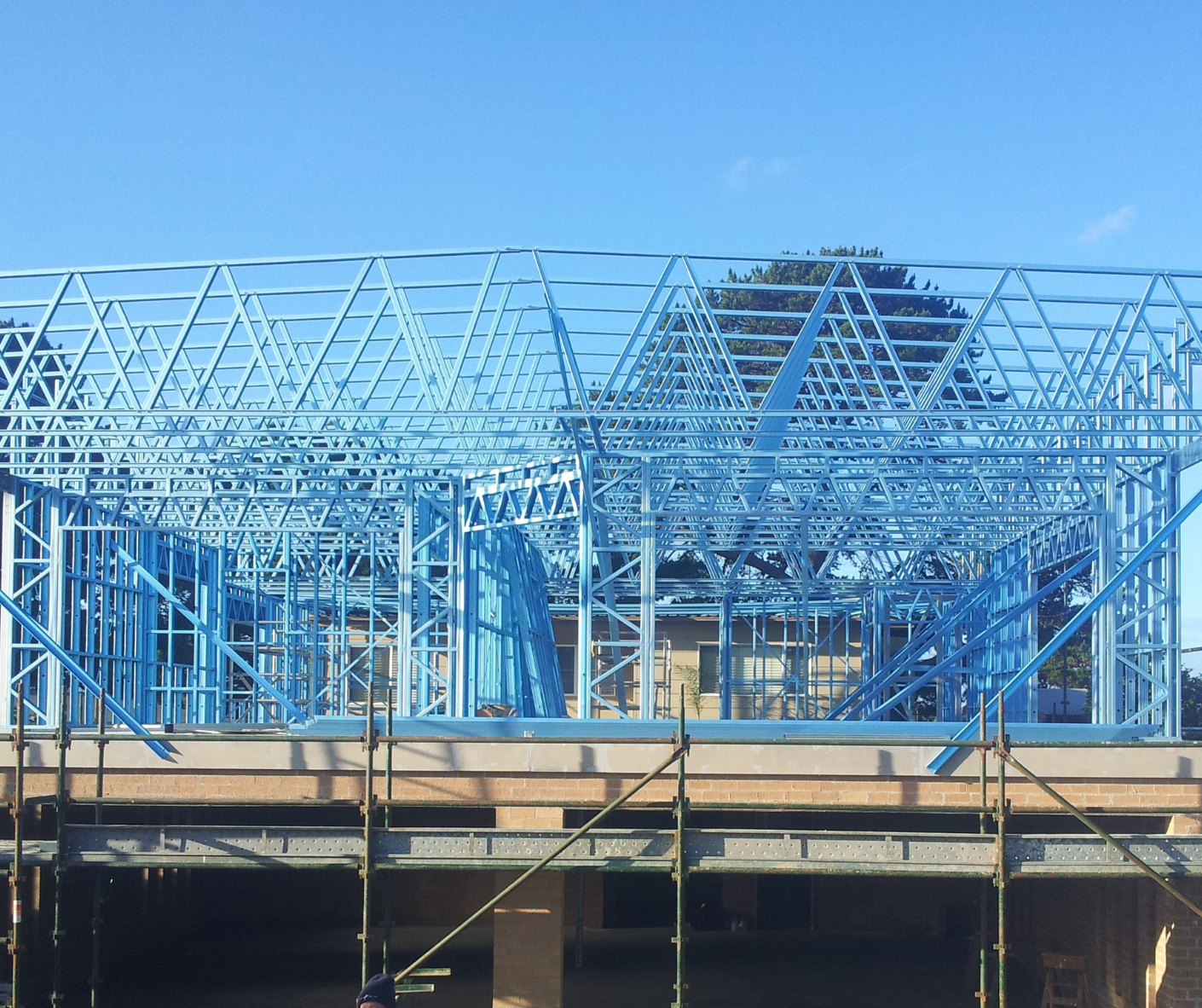 Blue steel frame of a building under construction against a clear sky