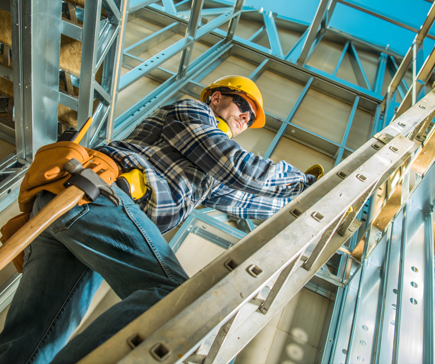 Worker in a yellow hard hat climbing a ladder inside a metal-framed structure