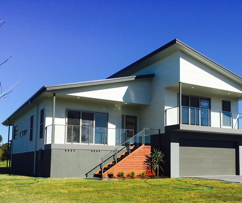 Modern two-story house with gray exterior, front stairs, and garage under a clear blue sky