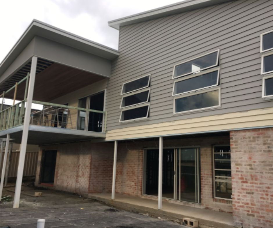Modern two-story brick and gray building exterior with balconies, large windows, and covered walkways