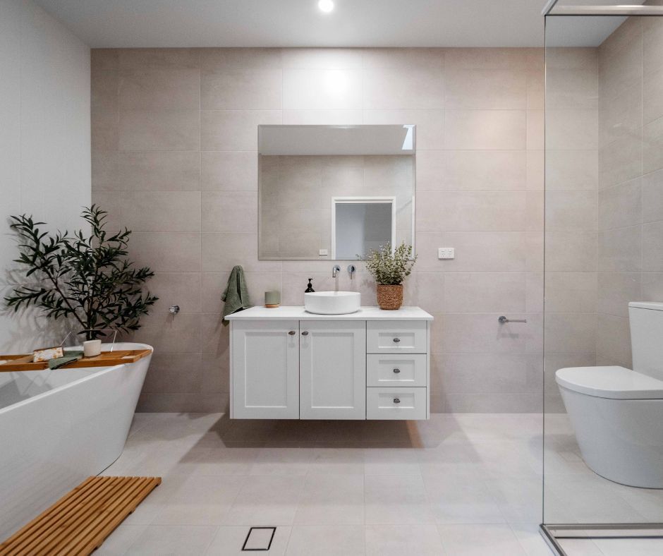Modern white bathroom with a floating vanity, bathtub, and glass shower. Neutral color palette.
