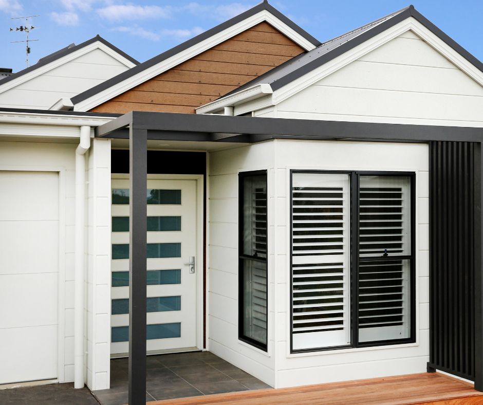 Modern white house entry with black trim, frosted glass front door, and shuttered windows