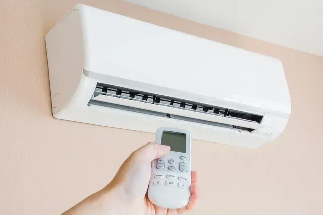 person-pointing-remote-at-air-conditioner.