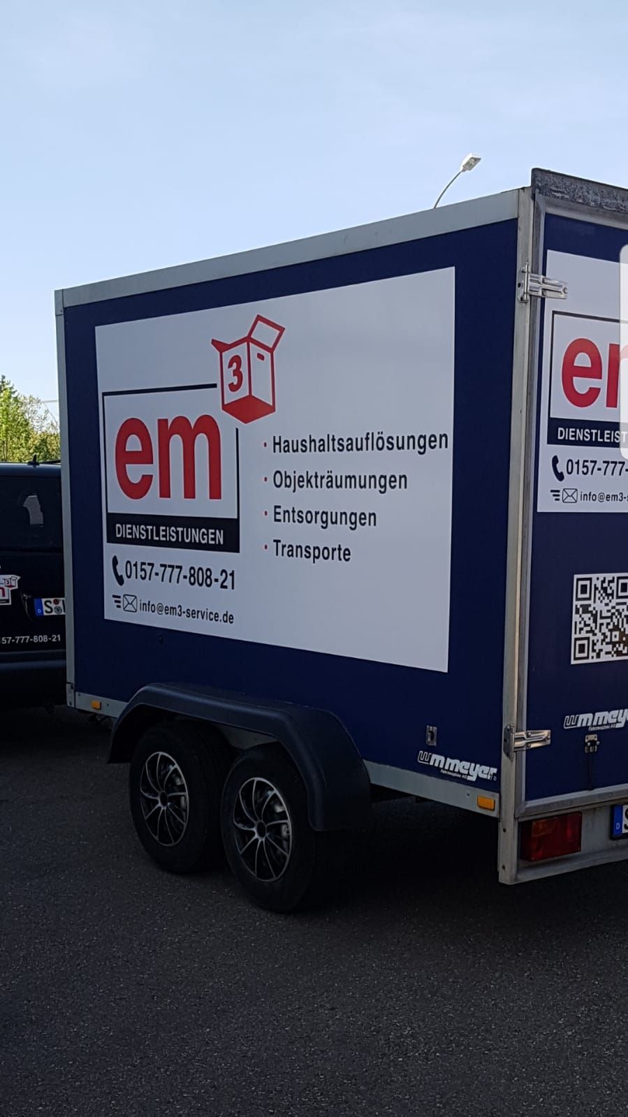 Ein blau-weißer Anhänger mit dem Wort „em3“ darauf der in Schorndorf steht.