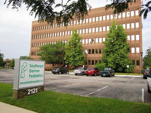 Exterior of Southeast Denver Pediatrics building with a sign and parked cars.