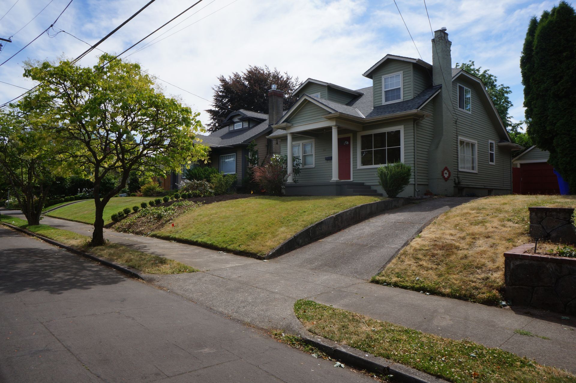 A house with a red door sits on the corner of a residential street.