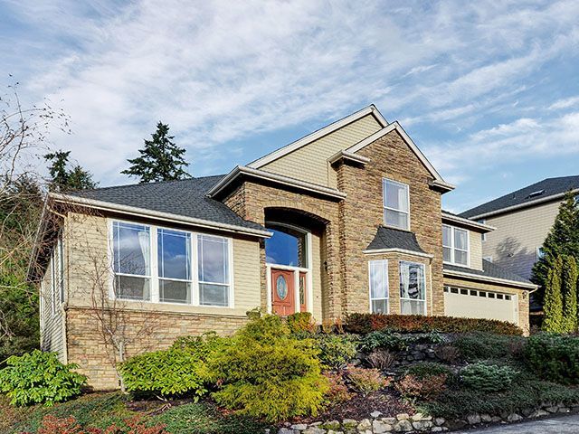 A large brick house with a red door is sitting on top of a hill.