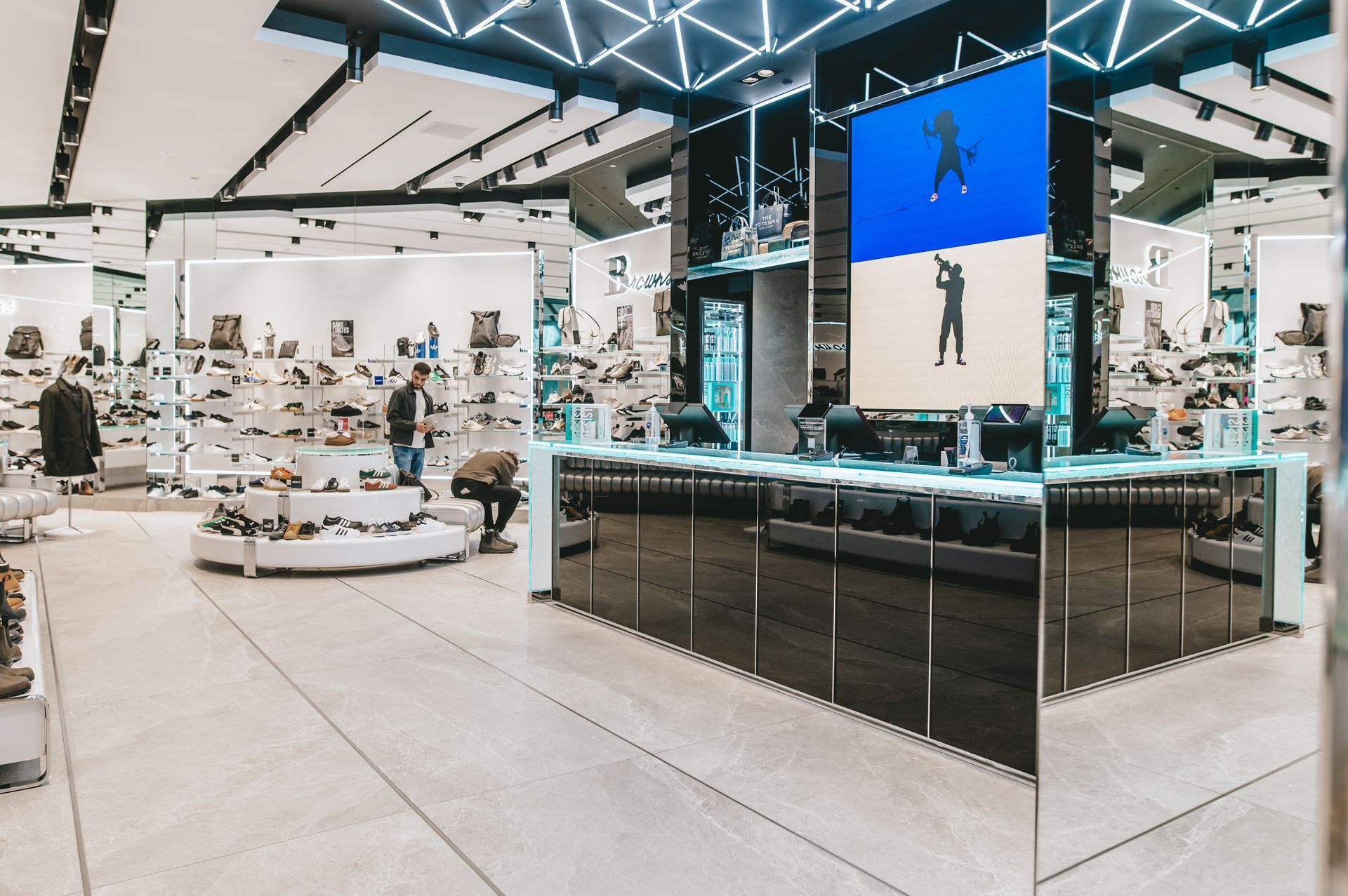 Un magasin de chaussures avec un grand écran suspendu au plafond.