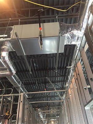 Construction site interior with HVAC ductwork, metal framing, and exposed ceiling.