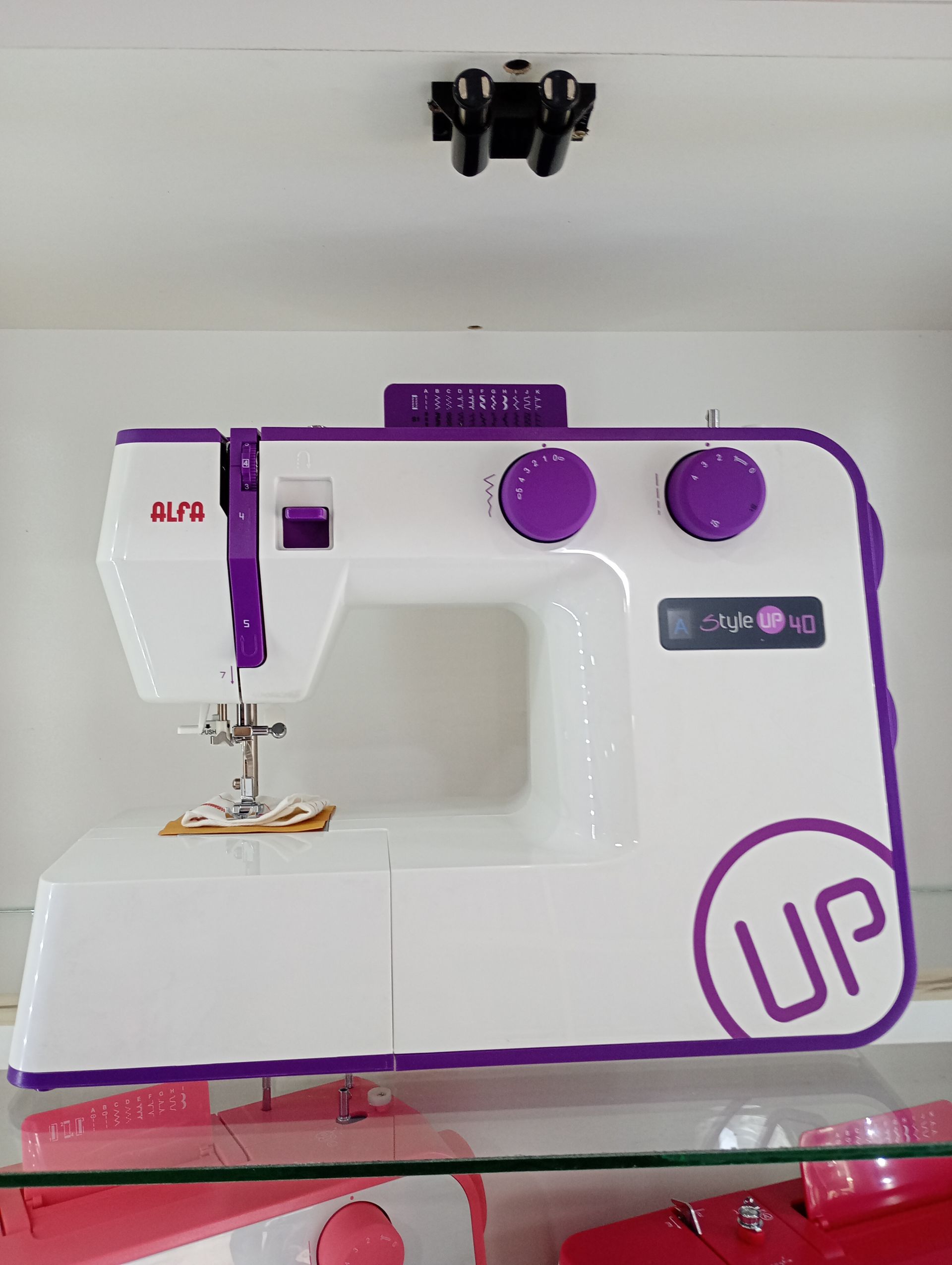 Máquina de coser blanca y morada en un estante. Marca 
