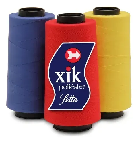 Tres carretes de hilo de poliéster Setta en azul, rojo y amarillo, dispuestos con el carrete rojo centrado en primer plano.