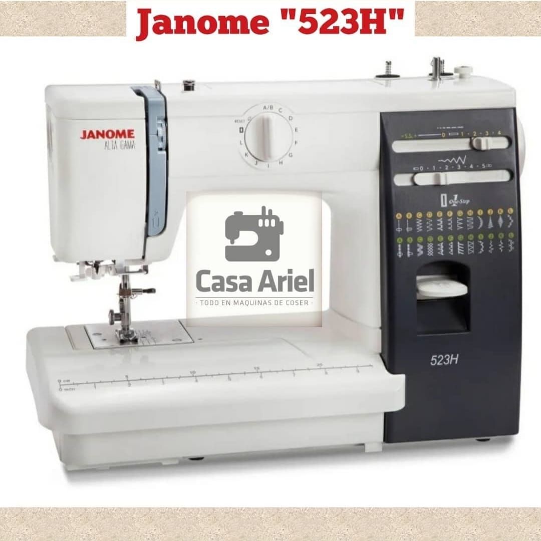 Máquina de coser Janome 523H blanca y negra. Incluye diales, panel de selección de puntadas y superficie de trabajo.