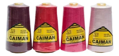 Cuatro bobinas de hilo de poliéster de la marca Caiman en tonos morado oscuro, rojo, rosa fucsia y rosa claro.