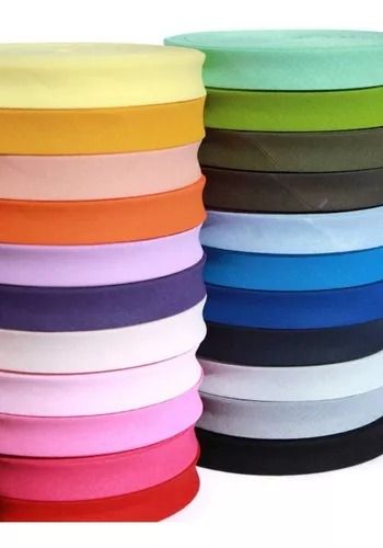 Dos pilas de carretes de cinta al bies de colores en varios tonos, incluyendo rojo, azul, verde y amarillo.