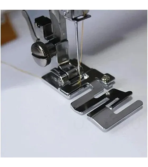 Primer plano del prensatelas de una máquina de coser con una guía metálica instalada, listo para coser.