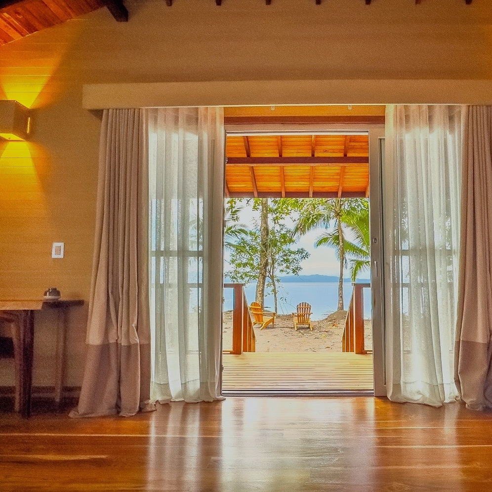 A room with a view of the ocean through a sliding glass door